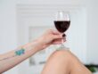Hand with tattoos holding glass of red wine. Swirling wine glass in wine tastings Red wine concept.